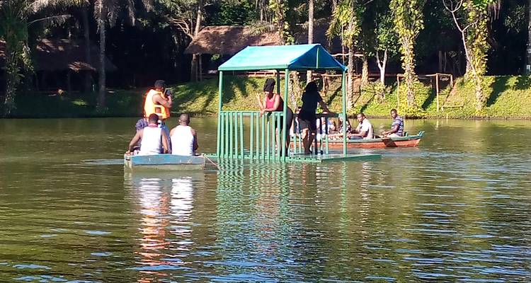 Menschen in kleinen Booten und einer schwimmenden Plattform auf einem ruhigen See.