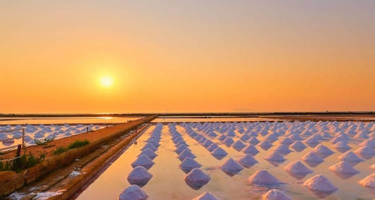 Vue du coucher de soleil sur les salines créant un reflet miroir.