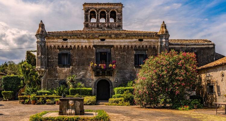 Bâtiment historique avec des plantes et des fleurs autour.