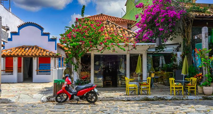 Colorful street with cafes, scooter, and flowering plants.