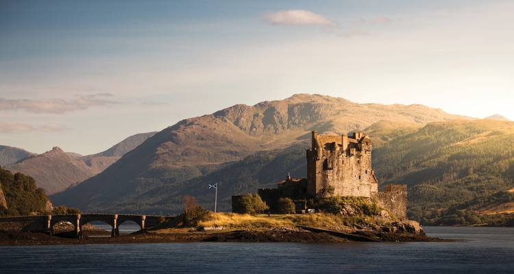 Eilean Donan Castle with mountains in the background, under a dramatic sky.