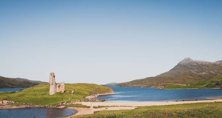 Ruined castle on an island surrounded by water and hills.