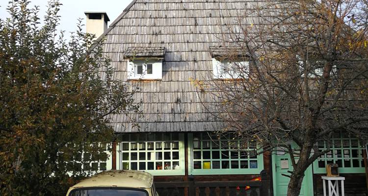 Maison traditionnelle avec un vieux véhicule garé.