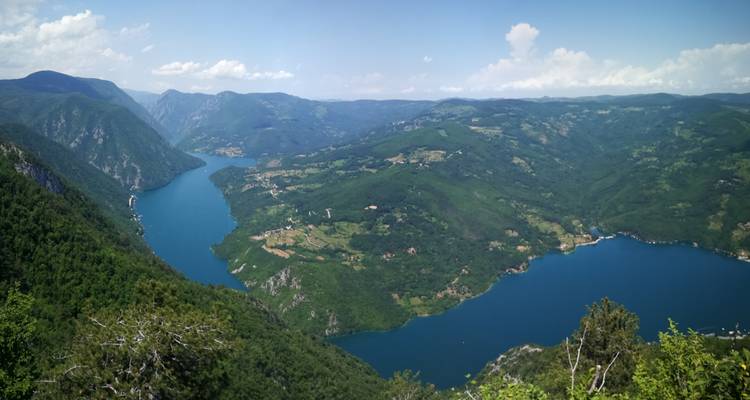 Vue panoramique d'une rivière entourée de montagnes verdoyantes luxuriantes.