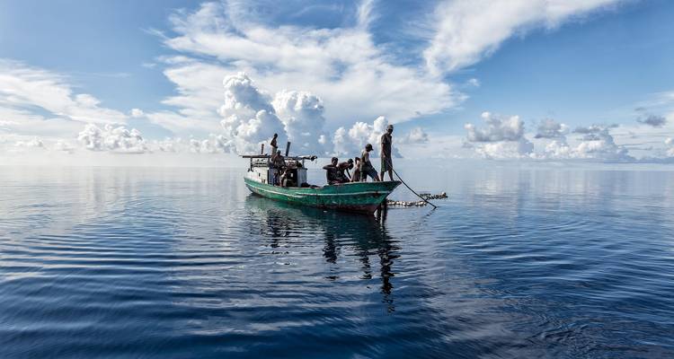 Personas en un barco de pesca en medio de un mar en calma.