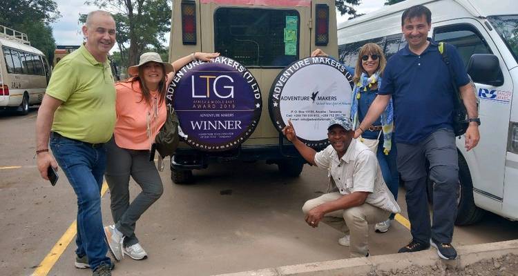 Groupe de personnes posant avec un véhicule ayant des logos visibles.