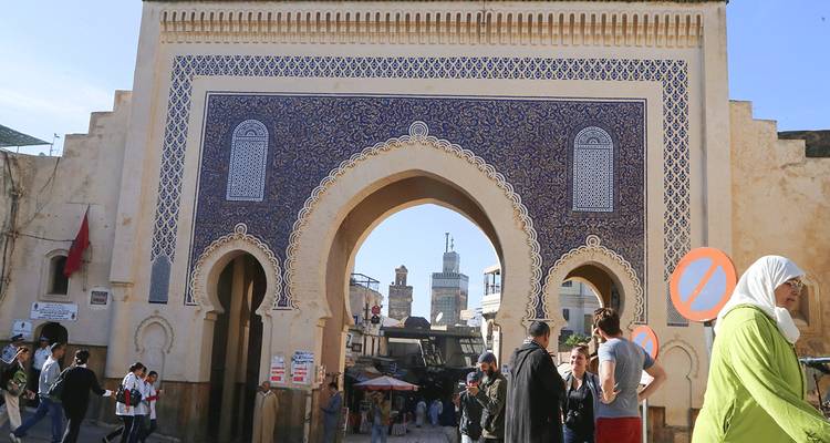 Entrée voûtée carrelée de bleu avec des personnes marchant au premier plan.