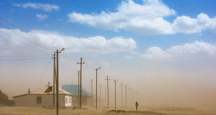 Paisaje desierto con líneas eléctricas y una tormenta de polvo.