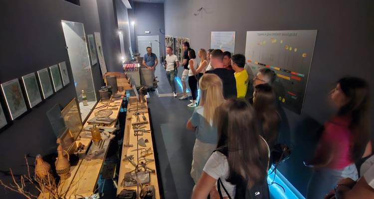 Des personnes observant une exposition historique dans une pièce faiblement éclairée.