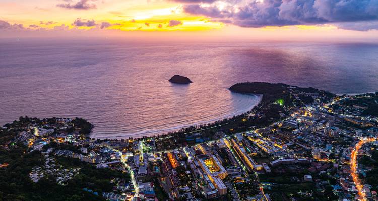 Vue aérienne d'une ville côtière sous un coucher de soleil vibrant.