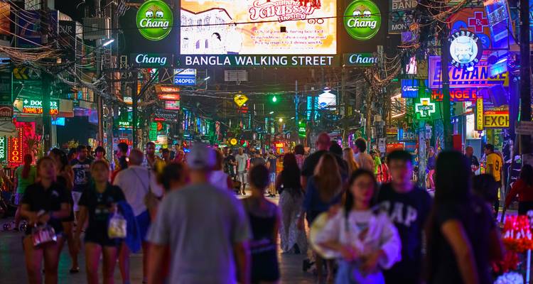Rue de marché nocturne bondée éclairée par des néons.