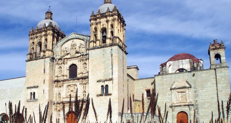 Historische stenen kerk met koepels onder een blauwe hemel