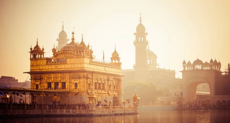 Templo Dorado de Amritsar al amanecer reflejándose en el agua.