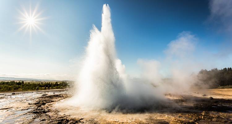 Geysir bricht unter einem sonnigen Himmel aus.