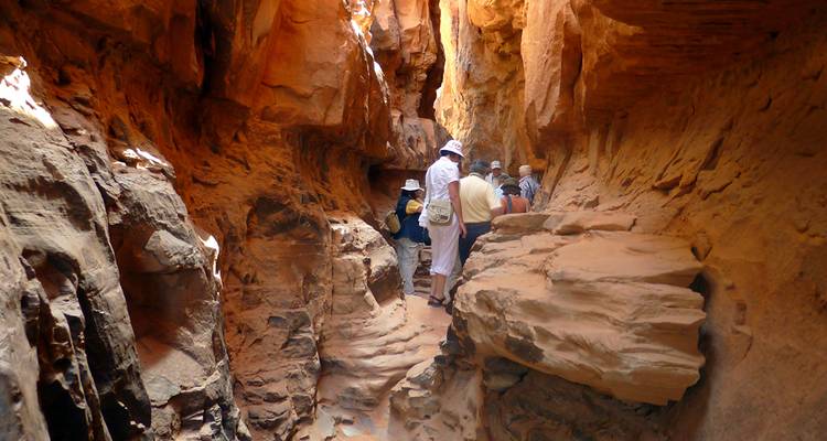Touristes grimpant à travers un passage rocheux étroit.
