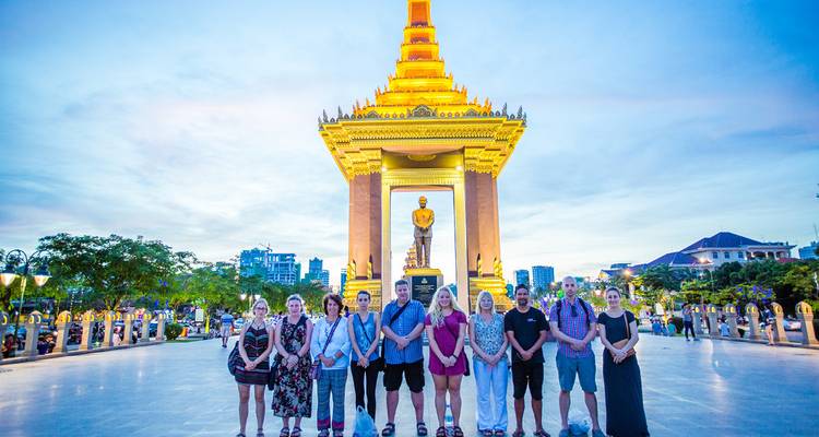 Grupo de pie frente a un monumento al anochecer.
