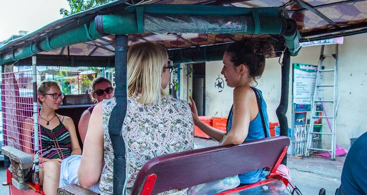 Turistas viajando en un tuk-tuk por una calle de la ciudad.