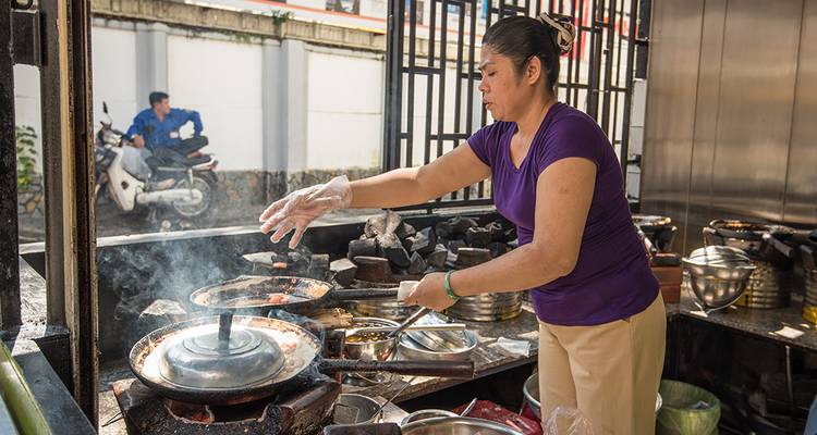Mujer preparando comida en un puesto de vendedor callejero.