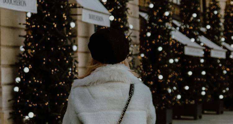 Personne en tenue d'hiver passant devant des arbres décorés.