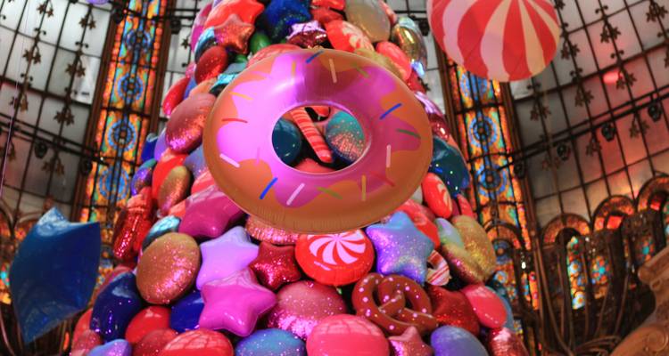 Décorations de Noël colorées à l'intérieur d'une zone commerciale avec des vitraux.