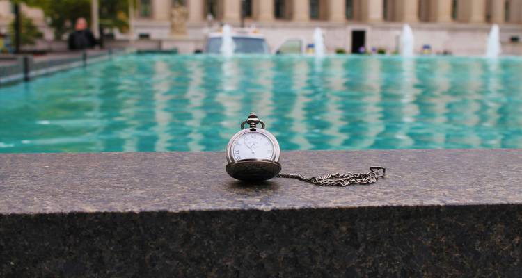 Une montre à gousset exposée près d'une fontaine.