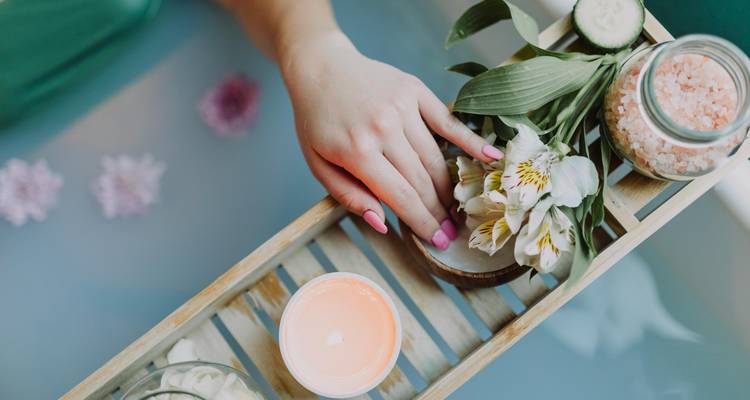 Configuration de bain relaxant avec fleurs et bougie sur plateau.