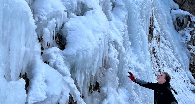 Personne admirant de gros glaçons sur une cascade gelée.