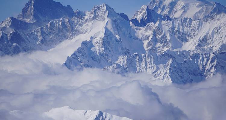 Sommets de montagnes enneigés au-dessus des nuages.
