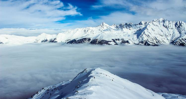 Chaîne de montagnes enneigée au-dessus des nuages.