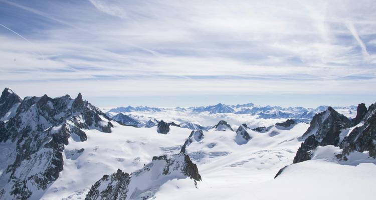 Vue large d'une chaîne de montagnes enneigée.