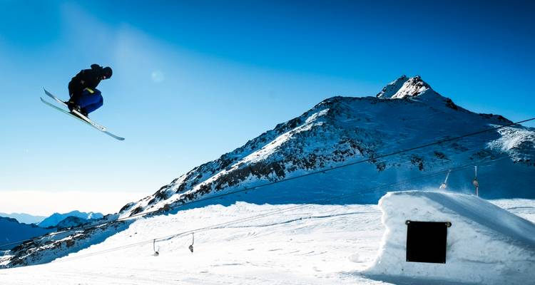Skieur en l'air au-dessus d'une pente enneigée.