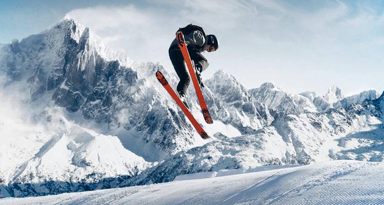 Sauteur à ski en plein vol avec panorama de montagne en arrière-plan.