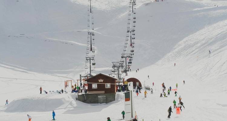 Domaine skiable avec remontées mécaniques, skieurs et pistes enneigées.