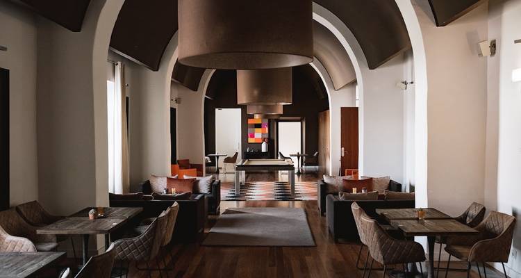 Stijlvolle moderne lounge met gewelfde plafonds, gedempte kleuren en gezellige zithoeken rond een centrale gang.