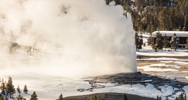 Geiser die uitbarst in een besneeuwd landschap.