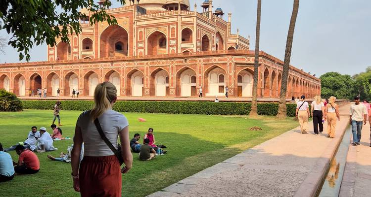 Los visitantes se relajan en los jardines frente a la Tumba de Humayún, hecha de arenisca roja, en Delhi en un día soleado.