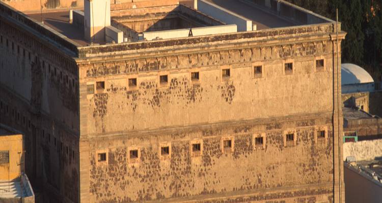 Vue extérieure d'un grand bâtiment historique en pierre avec de petites fenêtres.