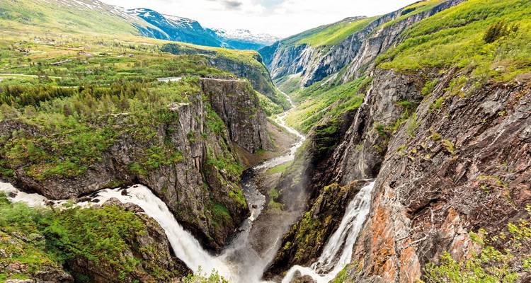 Luftaufnahme einer dramatischen Schlucht mit Wasserfällen und grünen Hügeln.