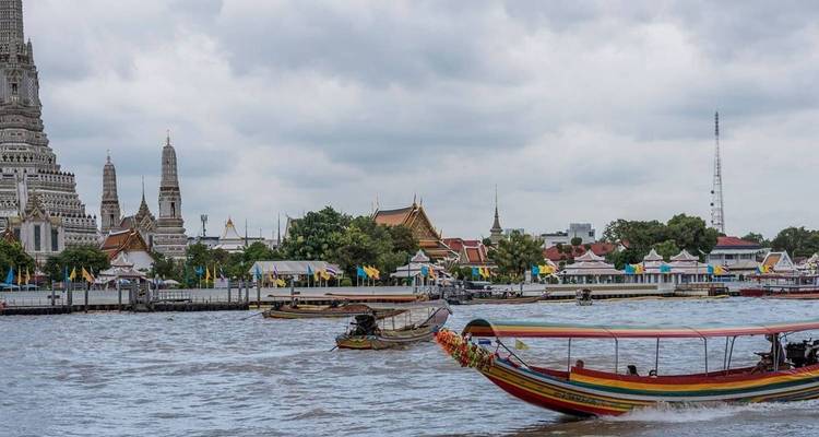 Des bateaux fluviaux et un temple sur la berge d'une rivière.