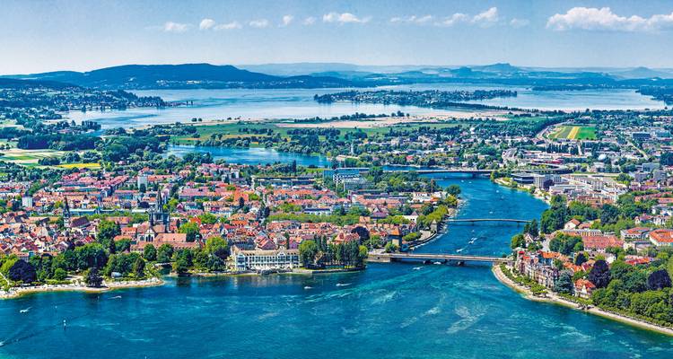 Vue aérienne d'une ville entourée d'eau avec des montagnes au loin.