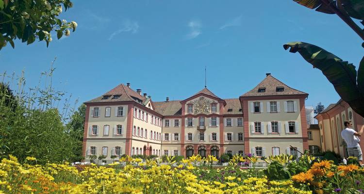Un grand bâtiment avec un jardin bien entretenu et un ciel bleu clair.
