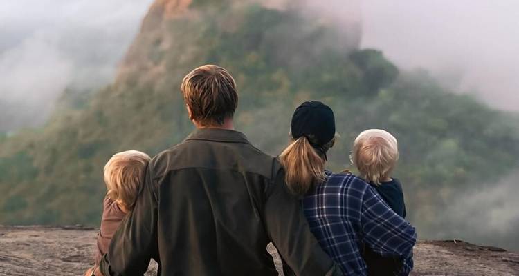 Familie die nevelige bergen observeert vanaf een uitkijkpunt.