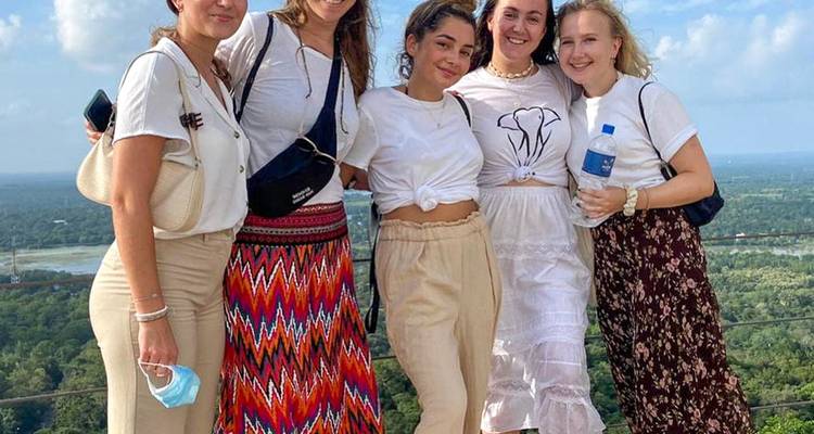 Groep van vijf mensen die poseren met een schilderachtig uitzicht op de achtergrond.