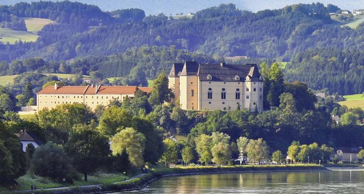 Vaste domaine ou palais entouré d'une végétation luxuriante surplombant une rivière.
