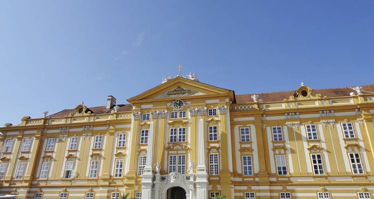 Gros plan de la façade d'un bâtiment de style baroque orné contre un ciel dégagé.