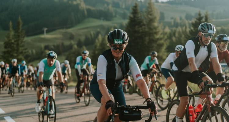 Cyclists posing on a road with forested hills in the background.
