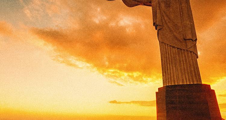 Statue of Christ against a vibrant sunset sky.