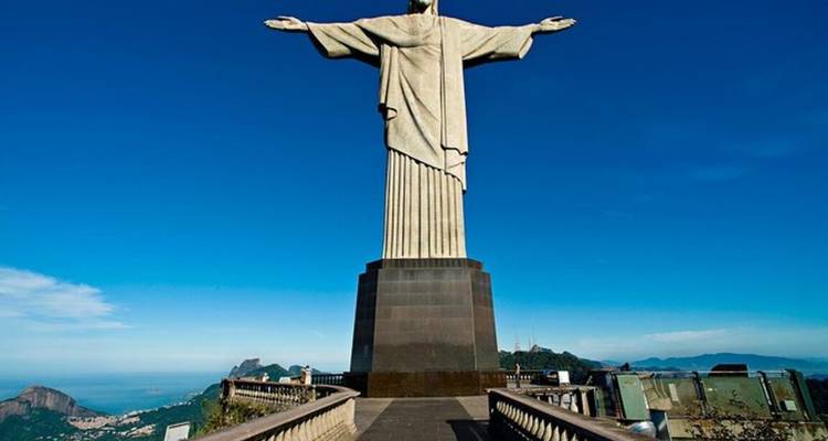 Ikonische Christus-der-Erlöser-Statue mit ausgebreiteten Armen vor einem klaren blauen Himmel.