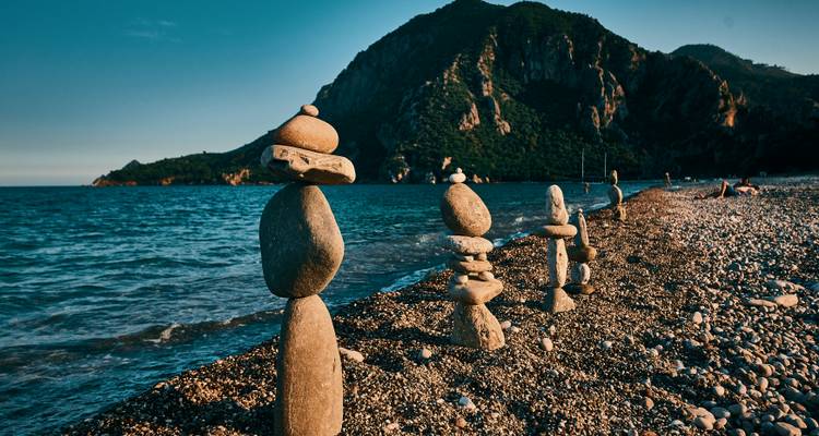 Balanced stone towers on a pebbly beach at sunset.