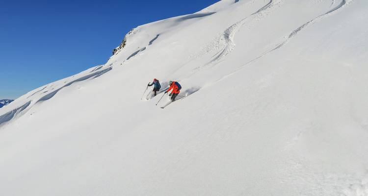 Two skiers on a pristine snow-covered mountain.
